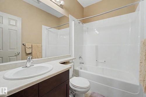 Bathroom featuring a vanity with a white oval sink, chrome faucet, and dark wood-finish cabinetry - 415 263 Macewan Road, Edmonton, AB 