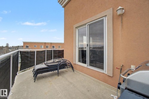 Private balcony with stucco exterior, sliding glass door, and metal railing - 415 263 Macewan Road, Edmonton, AB 