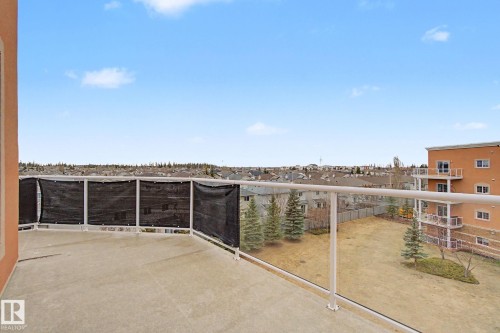 Expansive outdoor balcony featuring a concrete surface and a glass-paneled railing system with a privacy screen - 415 263 Macewan Road, Edmonton, AB 