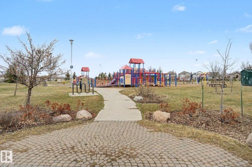 Community park featuring a large playground structure, open green spaces, paved pathways, and a bike rack - 415 263 Macewan Road, Edmonton, AB 