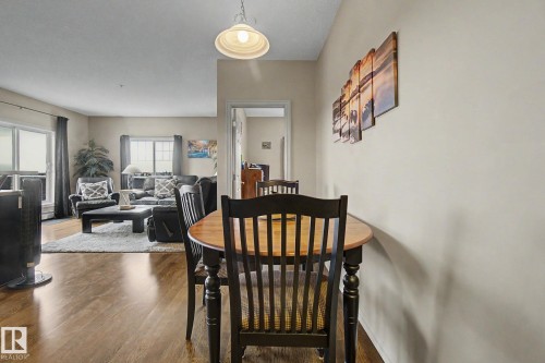 Open-concept living space featuring wood-finish flooring, recessed lighting, and a bright interior with multiple windows - 415 263 Macewan Road, Edmonton, AB 