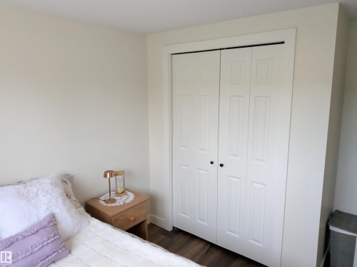 White bi-fold closet doors with black hardware, framed by white trim, and light-toned walls - 31 Brown Street, Stony Plain, AB 