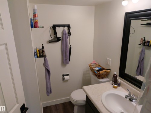 Bathroom featuring a white toilet, single vanity with integrated sink, chrome faucet, and a large mirror with a dark frame - 31 Brown Street, Stony Plain, AB 