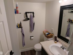 Bathroom featuring a white toilet, single vanity with integrated sink, chrome faucet, and a large mirror with a dark frame - 