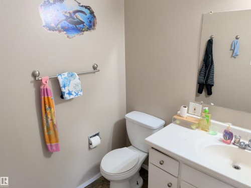 Bathroom with a white vanity and integrated sink, a wall-mounted mirror, and a toilet - 31 Brown Street, Stony Plain, AB 