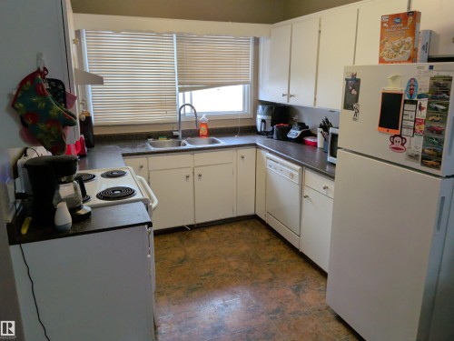 Efficient kitchen featuring white cabinetry, dark countertops, a double basin sink, and tile-finish flooring - 31 Brown Street, Stony Plain, AB 