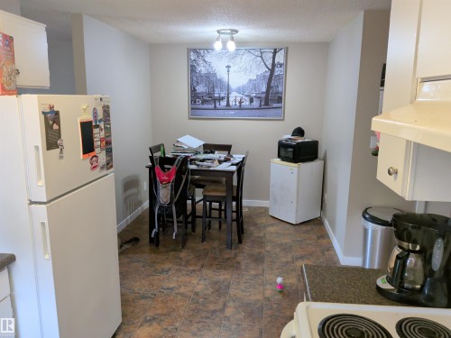 Kitchen with brown tile flooring, white upper and lower cabinetry, white appliances, and light neutral wall paint - 31 Brown Street, Stony Plain, AB 