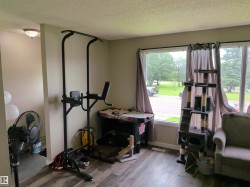 Spacious room featuring wood-finish flooring, light neutral wall paint, and a large window with white trim and dark curtain rods - 