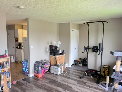 Open living space featuring wood-finish flooring, neutral wall tones, and a textured ceiling - 31 Brown Street, Stony Plain, AB 