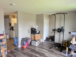 Open living space featuring wood-finish flooring, neutral wall tones, and a textured ceiling - 