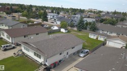 Residential property featuring a shingled roof, white siding, and an established neighborhood setting - 