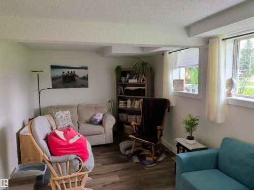 Living area featuring wood-finish flooring, two large windows, a built-in bookshelf, and a neutral color palette - 31 Brown Street, Stony Plain, AB 