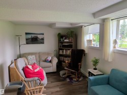 Living area featuring wood-finish flooring, two large windows, a built-in bookshelf, and a neutral color palette - 