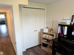 Interior space featuring wood-finish flooring, light-toned walls, and white bi-fold closet doors with black hardware - 
