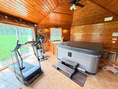 Indoor spa room featuring a vaulted wood-paneled ceiling, wood-finish walls, ceramic tile flooring, and large glass sliding doors - 26418 Twp Rd 633, Rural Westlock County, AB 