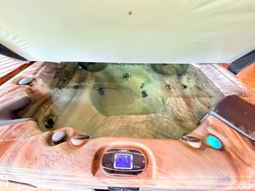 Outdoor spa featuring a textured wood-finish exterior, integrated control panel, multiple jets, and an open cover - 26418 Twp Rd 633, Rural Westlock County, AB 