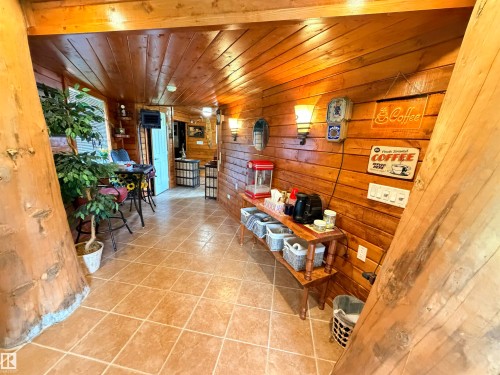 Wood-paneled interior featuring a built-in wood-finish shelving unit, ceramic tile flooring, and wall-mounted sconce lighting - 26418 Twp Rd 633, Rural Westlock County, AB 