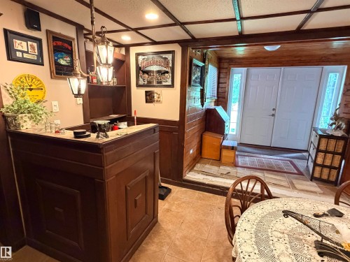 Custom-built wood bar with panel detailing, a light-toned countertop, and an overhead lantern-style light fixture - 26418 Twp Rd 633, Rural Westlock County, AB 