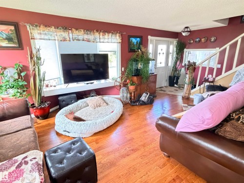Spacious living area featuring wood-finish flooring, a prominent front entrance with decorative glass, and a staircase with white balusters - 26418 Twp Rd 633, Rural Westlock County, AB 