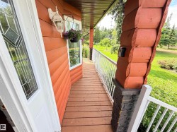 Expansive outdoor deck featuring wood-finish flooring, white railing, and a decorative column with stacked stone detailing - 
