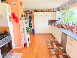 Full kitchen featuring wood-finish flooring and ample white cabinetry - 