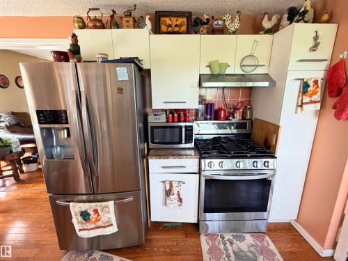 Kitchen featuring stainless steel French door refrigerator, gas range, microwave, and range hood - 26418 Twp Rd 633, Rural Westlock County, AB 