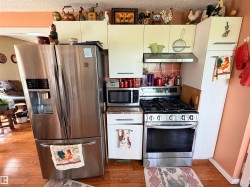Kitchen featuring stainless steel French door refrigerator, gas range, microwave, and range hood - 