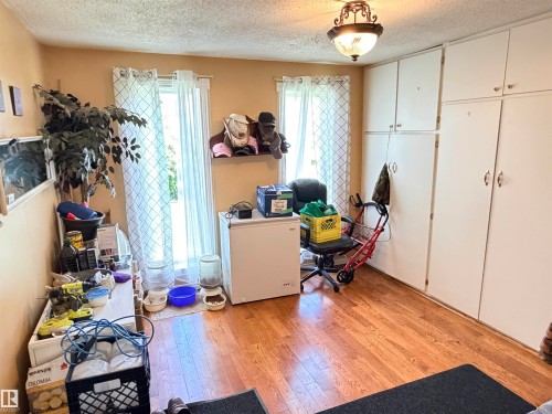 Room featuring wood-finish flooring, two windows with white curtains, a ceiling-mounted light fixture, and extensive built-in white cabinetry - 26418 Twp Rd 633, Rural Westlock County, AB 
