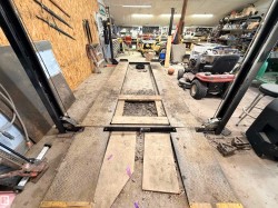 Automotive lift system with diamond plate platforms, wood-paneled walls, and overhead lighting - 