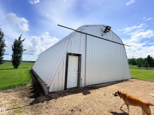 Corrugated metal quonset hut with a white entrance door, a gravel approach, and exterior lighting - 26418 Twp Rd 633, Rural Westlock County, AB 