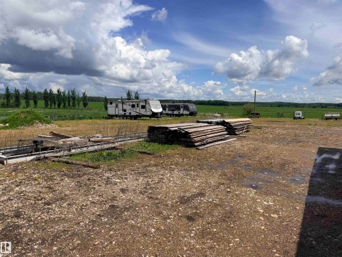 Expansive open lot with a gravel and dirt surface, featuring stacked timber and concrete forms - 26418 Twp Rd 633, Rural Westlock County, AB 