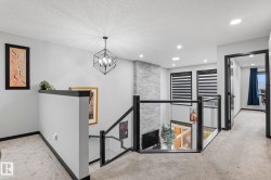 Upper-level landing featuring a modern geometric chandelier and recessed lighting - 