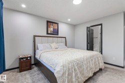 Spacious bedroom featuring light gray walls, plush gray carpeting, and recessed lighting - 