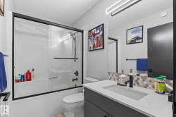 Bathroom featuring a shower-tub combination with black-framed sliding glass doors, black plumbing fixtures, and white subway tile surround - 