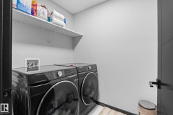 Dedicated laundry area featuring a wall-mounted shelf, light-toned walls, and dark-toned base trim - 