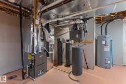 Mechanical room featuring a furnace, water heater, and water filtration system - 