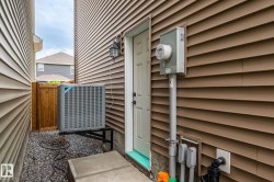 Brown horizontal siding with a utility door, exterior light fixture, and an outdoor HVAC unit on a gravel base - 