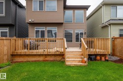 Expansive backyard featuring a multi-level wooden deck with baluster railings and steps descending to a grassy lawn - 
