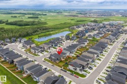 Aerial perspective of a modern residential development featuring numerous detached homes with dark roofs and light-toned siding - 