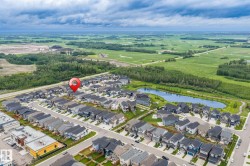 Aerial neighborhood perspective featuring residential properties, a central pond, and surrounding green spaces - 