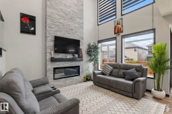 Living area featuring a tall stone-clad fireplace with a built-in electric firebox - 
