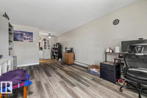 Spacious interior with wood-finish flooring, light neutral wall tones, and a textured white ceiling - 202 10330 113 Street, Edmonton, AB 