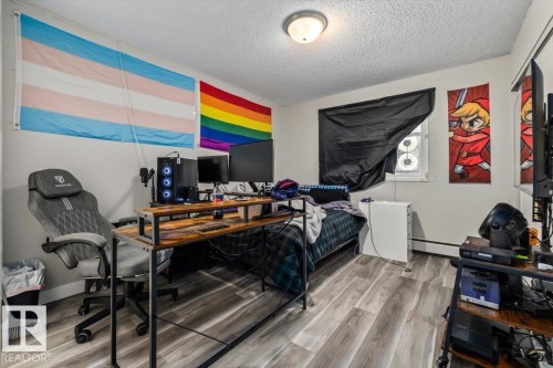 Bedroom featuring wood-finish flooring, a window with a dark covering, and a ceiling-mounted light fixture - 202 10330 113 Street, Edmonton, AB 
