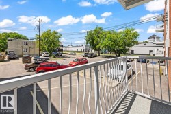 Balcony with white metal railing and a concrete surface, overlooking a paved parking area - 