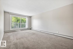 Spacious room featuring light gray carpeting, neutral wall paint, and white baseboard heating - 