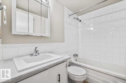 Bathroom featuring a white vanity with a light-colored countertop, an integrated sink, and a mirrored medicine cabinet - 306 10330 113 Street, Edmonton, AB 