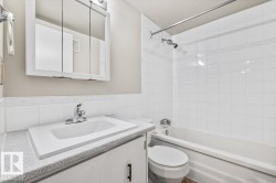 Bathroom featuring a white vanity with a light-colored countertop, an integrated sink, and a mirrored medicine cabinet - 