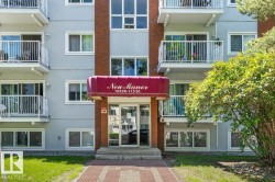 Multi-story building featuring light grey exterior siding, multiple private balconies with white railings, and a red awning over the main entrance - 