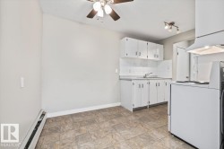 Open-concept kitchen and dining area featuring white cabinetry, a built-in sink, white tile backsplash, and patterned floor tiling - 