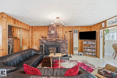 Living area featuring wood-paneled walls and a brick-faced fireplace with a built-in wood-burning insert - 1410 47436 Range Rd. 15, Rural Leduc County, AB 